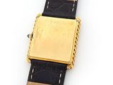 a gold watch with a black strap on a white surface