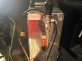 a beer dispenser sitting on a table next to a chair