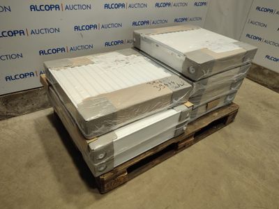 Plusieurs cartons contenant des matelas sont empilés sur une palette devant un mur.