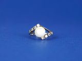a white pearl and diamond ring on a blue background