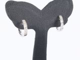 a pair of silver hoop earrings on a black stand