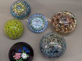 six different colored glass balls sitting on a white surface