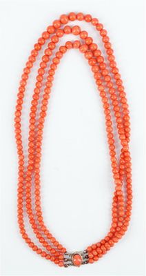 un collier de perles orange muni d'un fermoir en argent, sur fond blanc