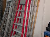 many ladders stacked up in a garage next to a tool box