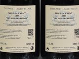 two bottles of wine sitting on top of a table next to each other