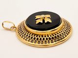 an image of a black and gold pendant with a flower on it
