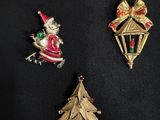 three christmas pins on a black surface with a christmas tree