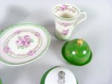 a green plate with a picture of a woman on it next to a cup and saucer and a plate with a picture of a woman on it