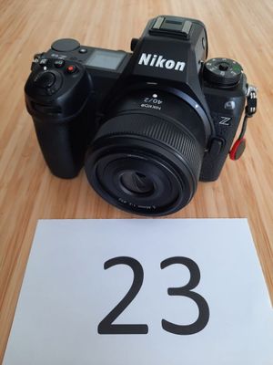 un appareil photo noir posé sur une table à côté d'une feuille de papier blanche