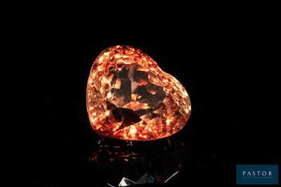 an orange diamond on a black surface with a black background