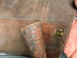 a person holding a brown leather belt with a metal buckle