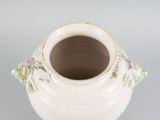 a white vase with flowers on it on a table