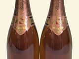 two bottles of champagne sitting next to each other on a white surface
