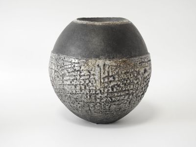 un vase noir et blanc posé sur une surface blanche
