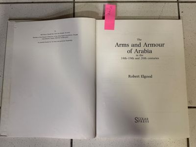 un livre ouvert posé par terre, sur lequel est posé un post-it rose