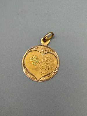 un gros plan d'un pendentif en forme de cœur en or orné d'une fleur