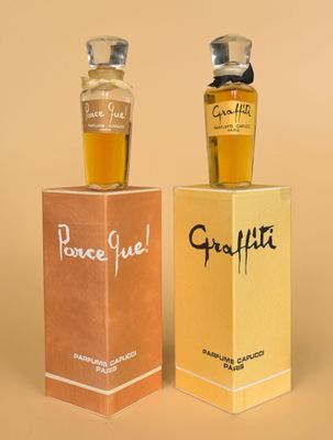 two bottles of perfume sitting next to each other on top of a box