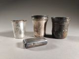 trois tasses en argent et un briquet sont posés sur une table