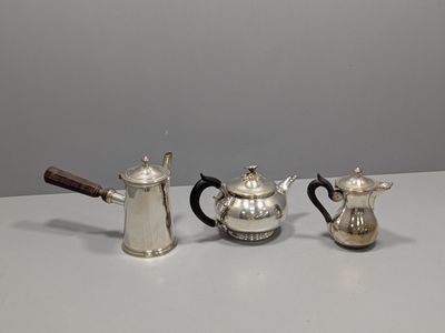 deux théières en argent et une cafetière posées sur une table