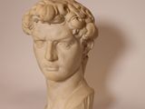 marble bust of a man with curly hair on a white background