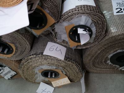 many rolls of fabric on the floor with price tags on them