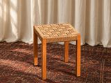 un gros plan sur un petit tabouret posé sur un tapis devant un rideau