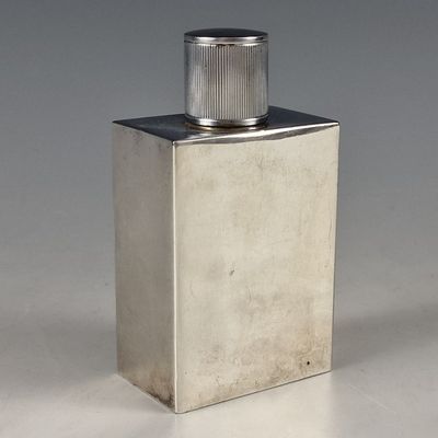 une image représentant une bouteille argentée munie d'un bouchon métallique, posée sur une surface blanche