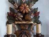 une applique murale sur laquelle sont posées deux bougies et une corbeille de fruits