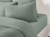 an image of a bed with a green comforter and pillows