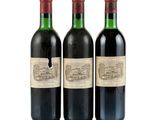 three bottles of red wine sit next to each other on a white surface