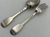 deux cuillères et une fourchette en argent sur une surface blanche