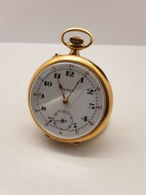 l'image d'une montre de poche en or posée sur une surface blanche