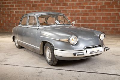 a silver car that is parked in front of a brick wall