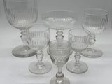 six clear glass goblets sitting on top of a white table