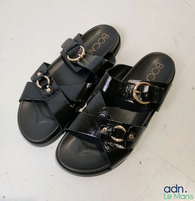 pair of black sandals with gold buckles on a white surface