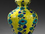 un vase jaune orné de fleurs bleues, posé sur une table