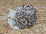 un chapeau orné de perles noires et blanches posé sur une table