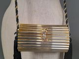 gold and black clutch bag with tassels on mannequin torso