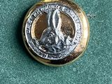 un bouton doré orné d'un lapin, sur un fond vert