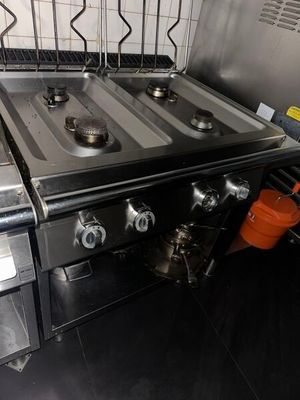 stainless steel stove top with two burners and a pot on the side