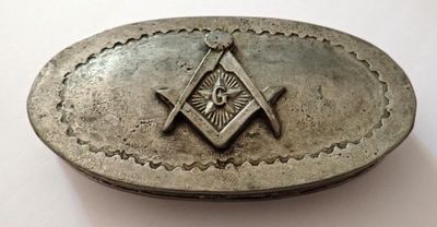 une boucle de ceinture en métal ornée d'un symbole maçonnique