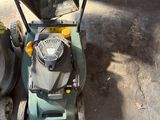 a lawn mower that is sitting on the ground next to a trash can