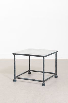 une table basse au plateau en marbre blanc, avec des pieds en métal noir