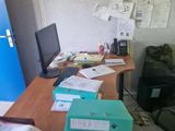 a desk with a computer, a laptop, and many files on it