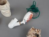 a white vase with a red flower on it next to a pair of white shoes and a green string