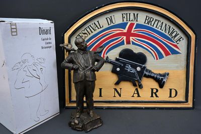une statue représentant un homme tenant un pistolet, à côté d'un panneau