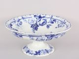 a blue and white bowl on a pedestal on a table