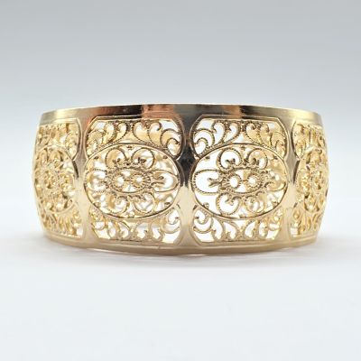gros plan d'un bracelet en or sur une surface blanche