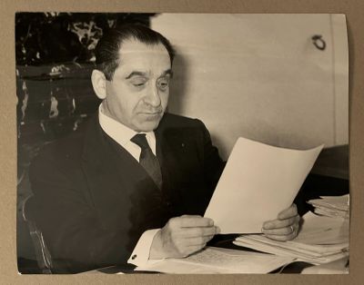photographie en noir et blanc d'un homme en costume en train de lire un bout de papier
