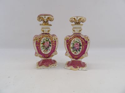 pair of pink and gold vases with flowers on them on a white surface